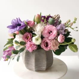 Pink and purple mixed bouquet in a textured gray vase