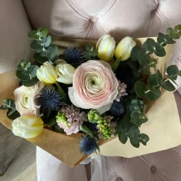 Bouquet of pale tulips and ranunculus with eucalyptus and blue thistle