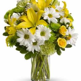 Yellow lilies and white daisies in a clear glass vase