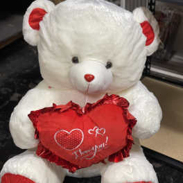 White teddy bear holding a red heart with "I love you" text
