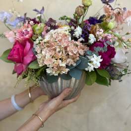 Mixed bouquet in a ribbed vase with pink, white, and purple blooms