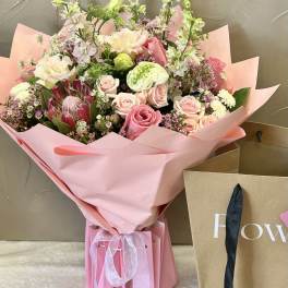 Pink bouquet with roses and mixed blooms wrapped in pink paper