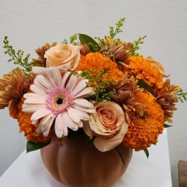 Orange and peach flowers arranged in a pumpkin-shaped vase