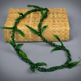 Braided green vine garland draped over a woven straw clutch