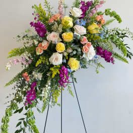 Large standing floral spray with multicolored roses and cascading greenery