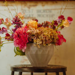 Mixed bouquet of pink, peach, and purple flowers in a gray vase