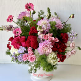 Mixed pink and red flower arrangement in a white vase