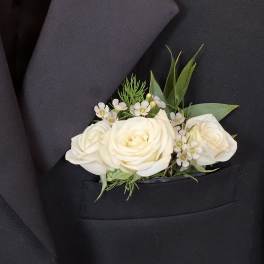 White rose pocket boutonniere with small white flowers in a black suit jacket pocket