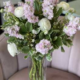 Pink stock and white ranunculus in a clear glass vase