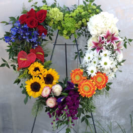 Heart-shaped floral wreath on an easel with mixed bright flowers