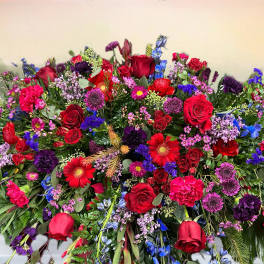 Large mixed floral spray with red roses, purple blooms, and blue flowers