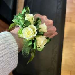 White rose wrist corsage with green ribbon and netting