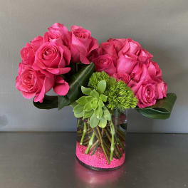Pink roses arranged in a clear glass vase with a succulent accent