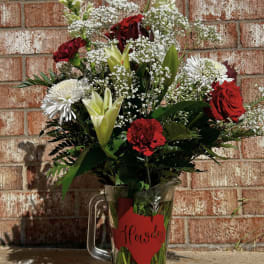 Red and white mixed flower arrangement in a glass pitcher