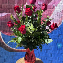 Tall arrangement of red roses in a shiny red vase on a small round table