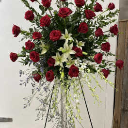 Tall standing spray of red roses and white lilies on a metal easel
