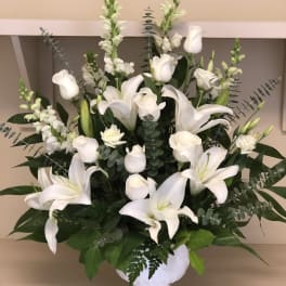 White lilies and roses arranged in a white vase