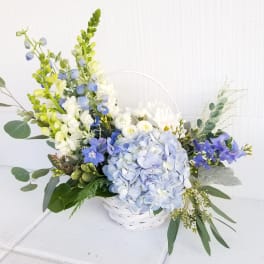 Blue and white floral arrangement in a white basket