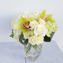 White and pale yellow floral arrangement in a clear glass vase