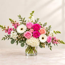 Pink and white roses with gerbera daisies in a clear glass vase