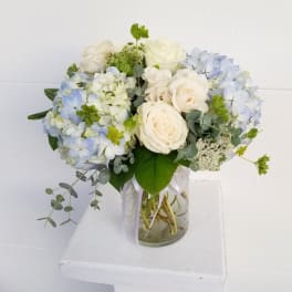White and pale blue flower bouquet in a glass vase
