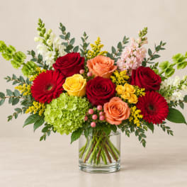 Mixed bouquet of roses, gerbera daisies, and hydrangea in a glass vase