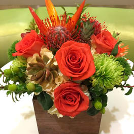 Orange roses and tropical blooms in a wooden box