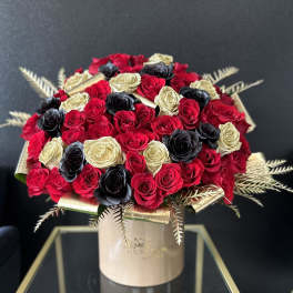 Bouquet of red, black, and gold roses in a round box