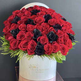 Round bouquet of red and black roses in a white hat box