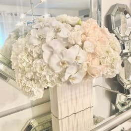 White and blush floral arrangement in a tall white vase