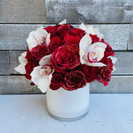 Red roses and white orchids arranged in a white vase