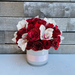 Red roses and white orchids in a round white box