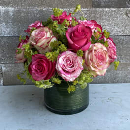 Pink and cream roses arranged in a green round vase