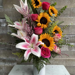 Pink roses and lilies with sunflowers in a white vase