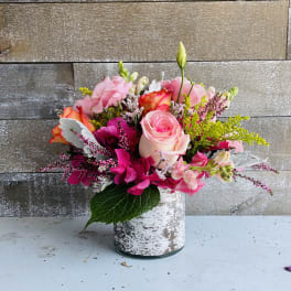 Pink and orange mixed flower arrangement in a white vase