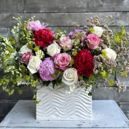 Mixed pink, white, and red flowers in a white textured vase