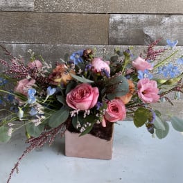 Pink roses and blue flowers in a square metallic vase