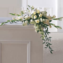 White floral casket spray with trailing greenery