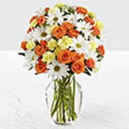 Bouquet of orange roses and white daisies in a clear glass vase
