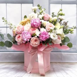 Pink and white roses in a pink hat box with a ribbon