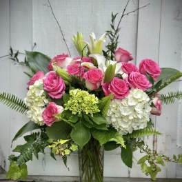 Pink roses and white lilies in a glass vase with white hydrangeas