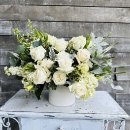 White rose arrangement in a white vase with silver foliage