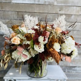 Mixed bouquet of white, peach, and brown roses in a glass vase