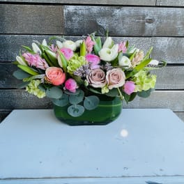 Mixed pink and white flower arrangement in a green glass vase