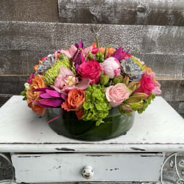 Colorful mixed flower arrangement in a low green glass bowl