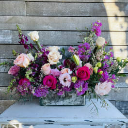 Large mixed bouquet of pink, purple, and white flowers in a rectangular vase