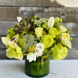 Green and white floral arrangement in a glass vase
