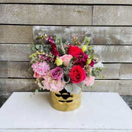 Mixed pink and red flower arrangement in a gold vase