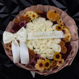 Bouquet of white roses and autumn mums with a small pumpkin and ribbon