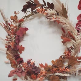 Autumn wreath with dried leaves and grasses in rust and burgundy tones